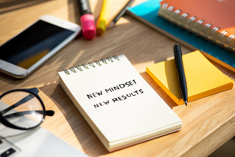 A notebook with the words "new mindset new results" sits on a desk to represent the change one can expect through hypnotherapy for stress management.